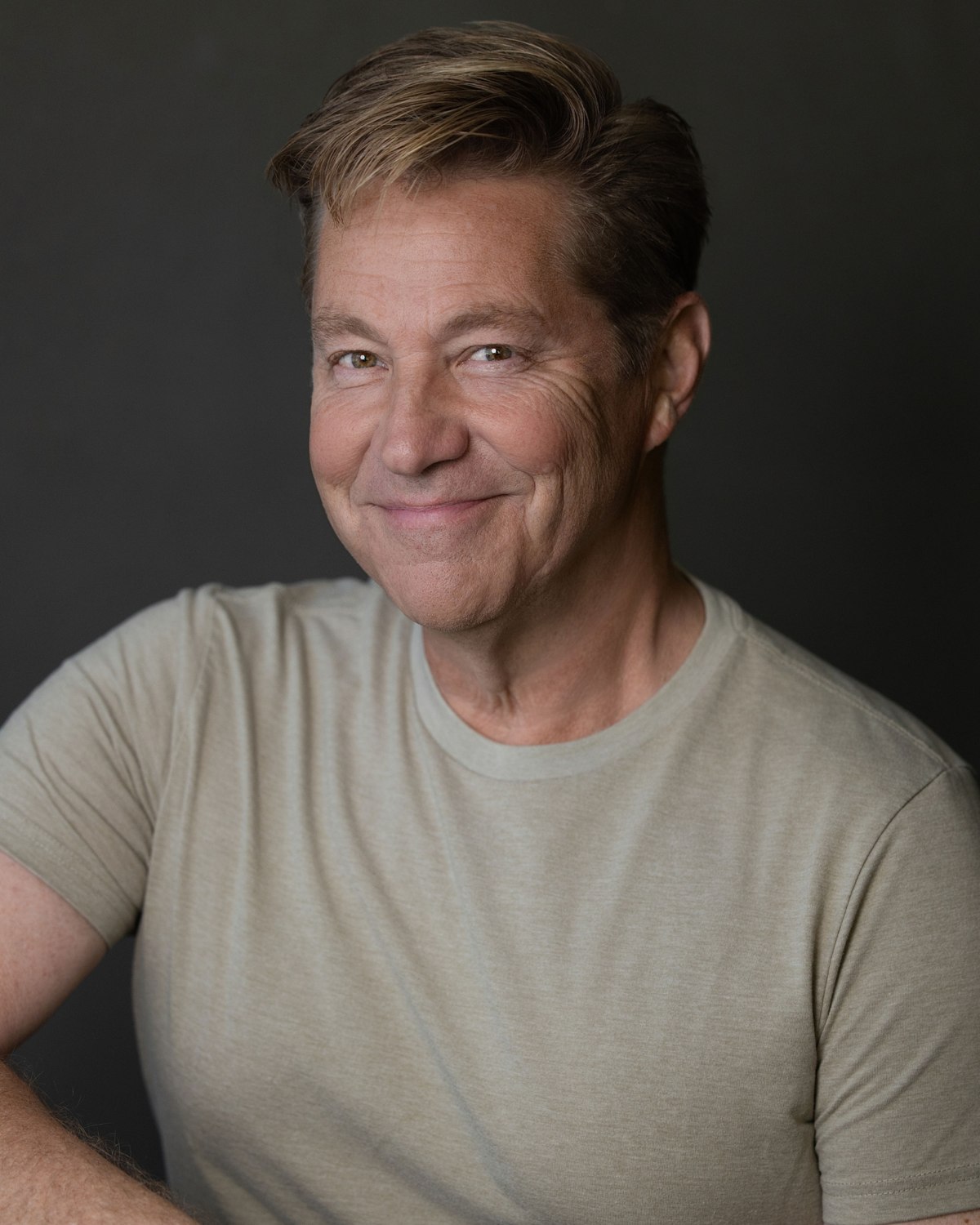 Portrait of a man in a casual neutral shirt against a dark backdrop
