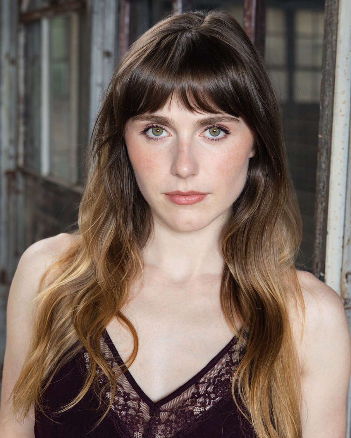 Outdoor headshot of a woman with long brown hair and bangs