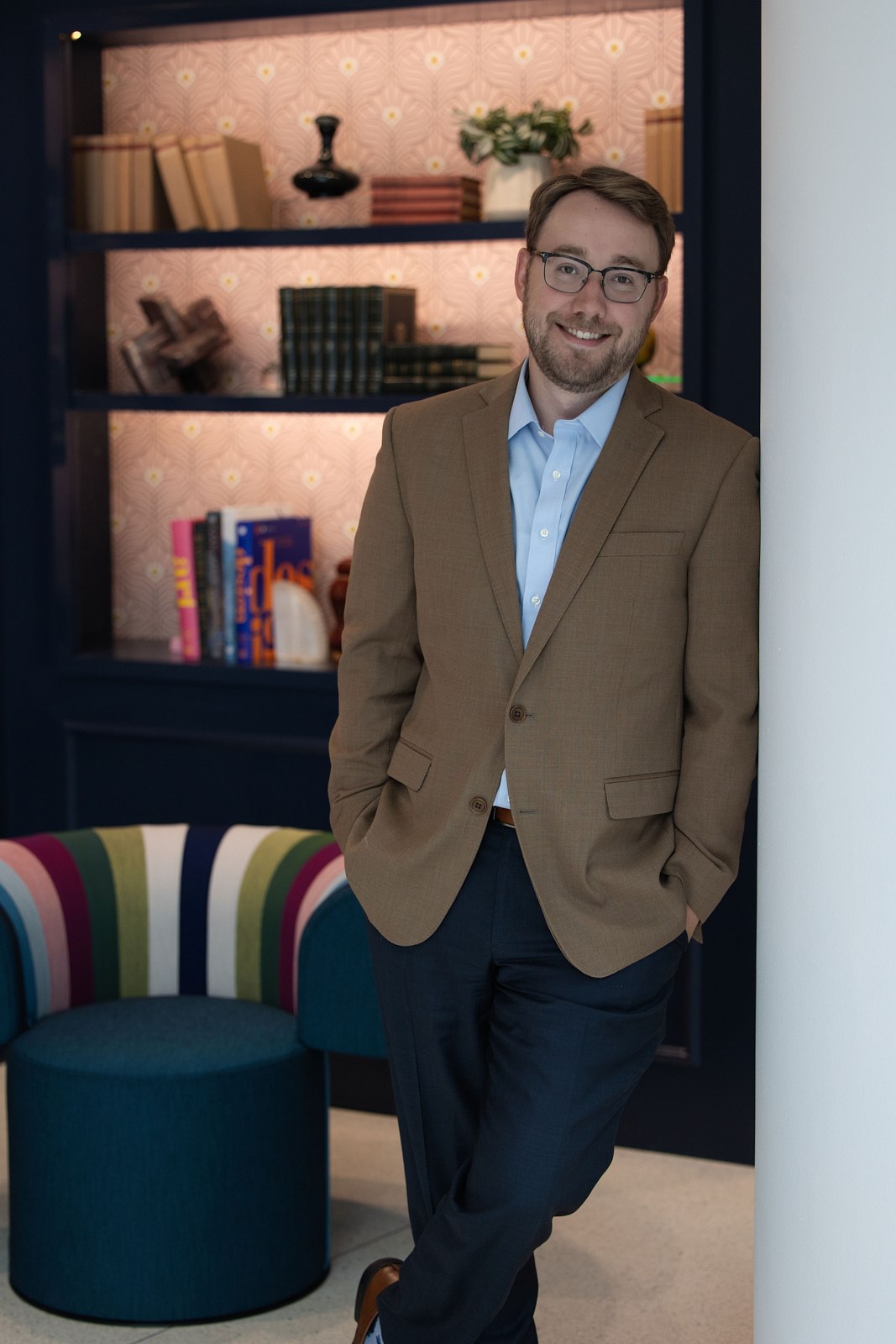 Environmental portrait of a man in a tan blazer in a lounge