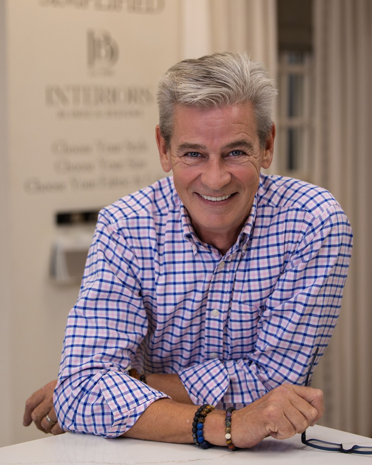 Portrait of a smiling man in a checkered shirt at a desk