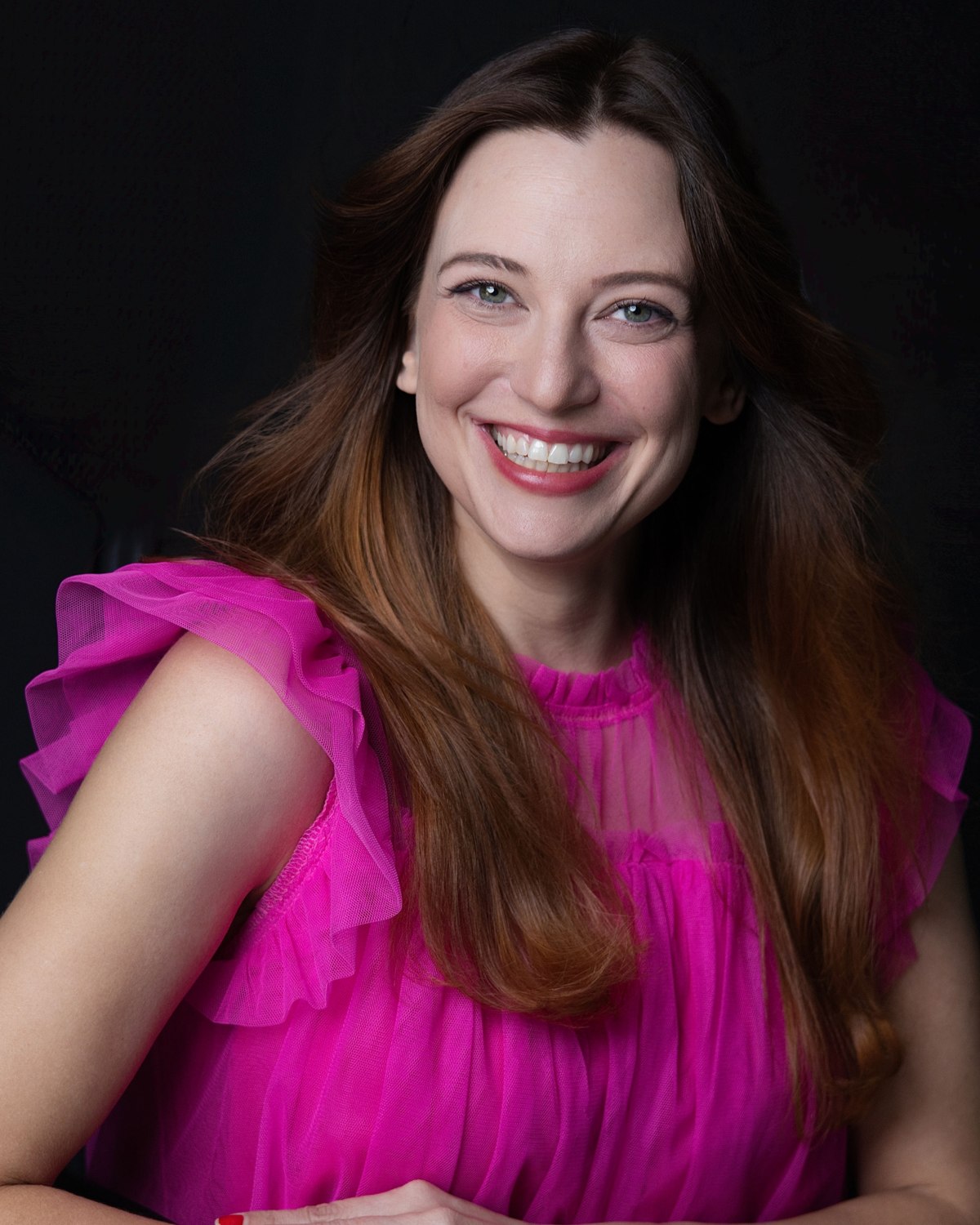 Studio portrait of a smiling woman in a bright pink blouse