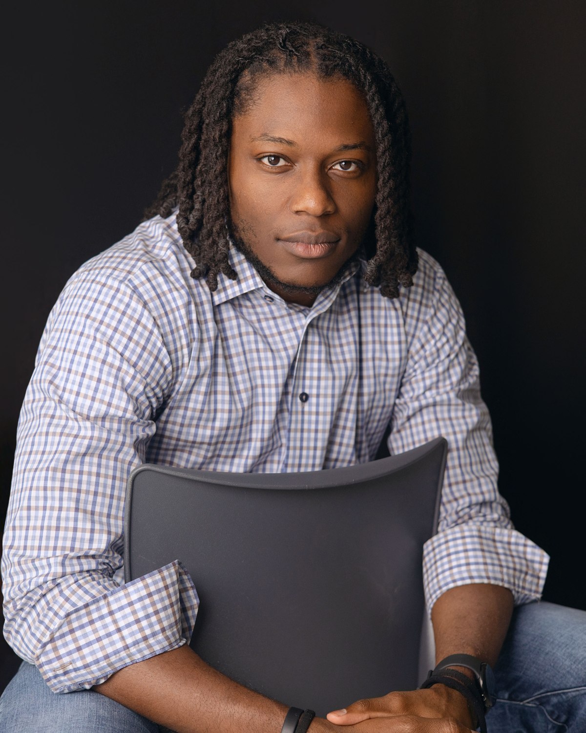 Seated studio portrait of a man in a checkered shirt