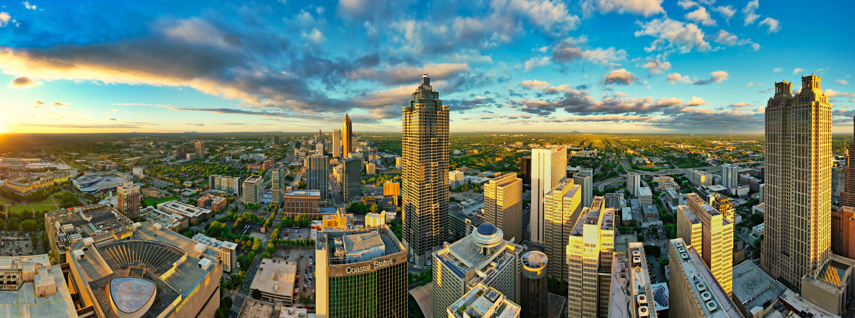 Wide view of the Atlanta skyline in warm sunset light beneath blue skies