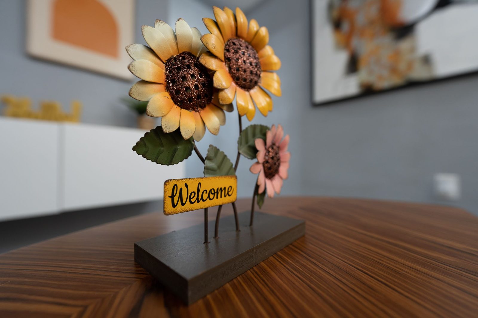 A welcome sign with sunflowers on a wooden table.