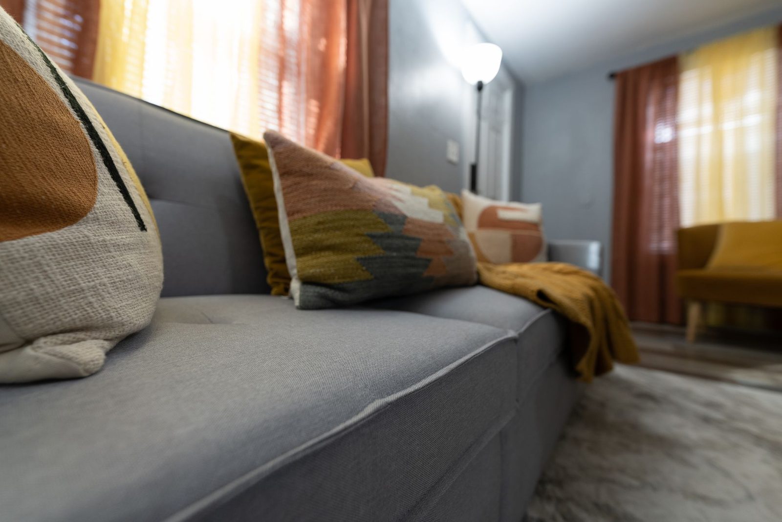 A living room with a gray couch and yellow chair.