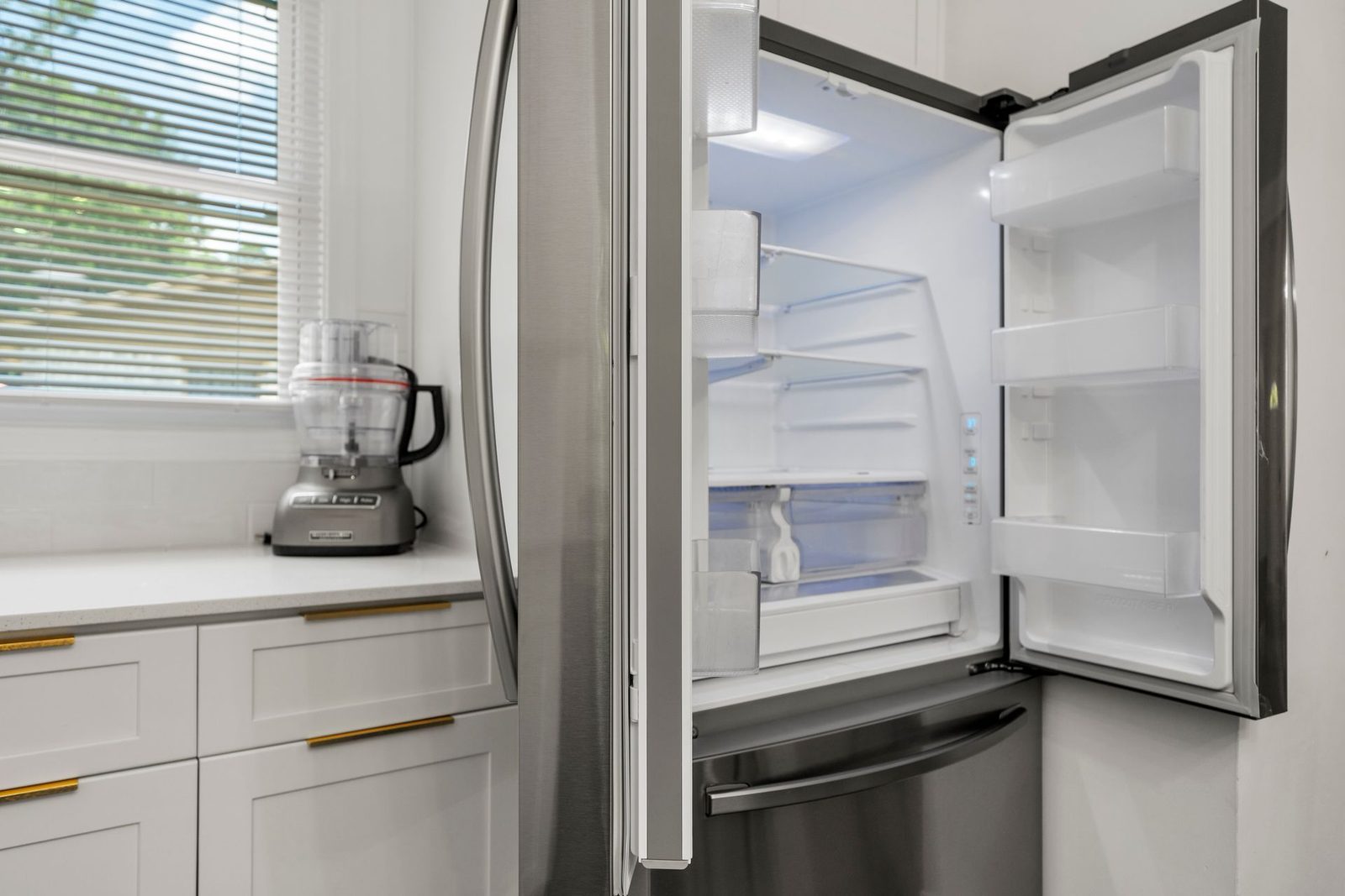 A stainless steel refrigerator with the door open in a kitchen.