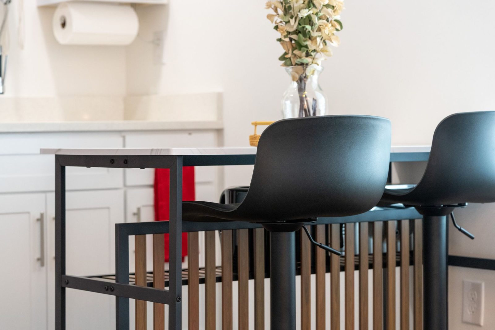 A kitchen with a table and chairs and a vase of flowers on it.