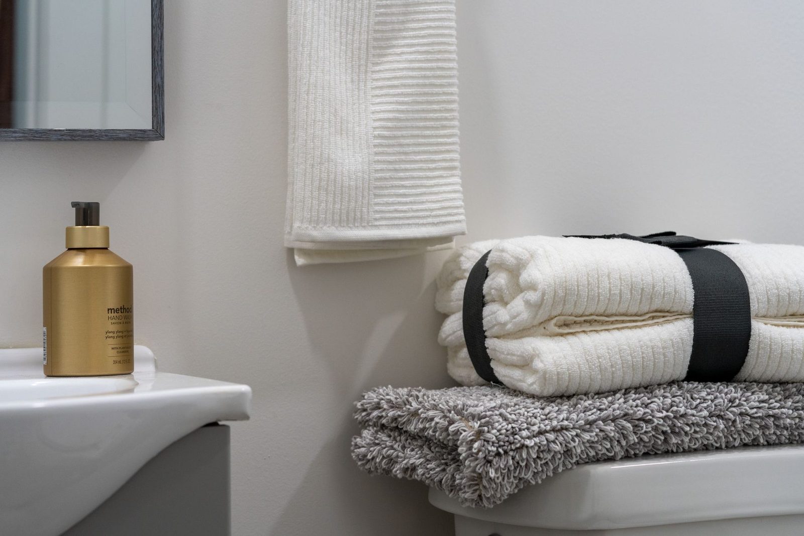 A bathroom with towels stacked on top of a toilet.