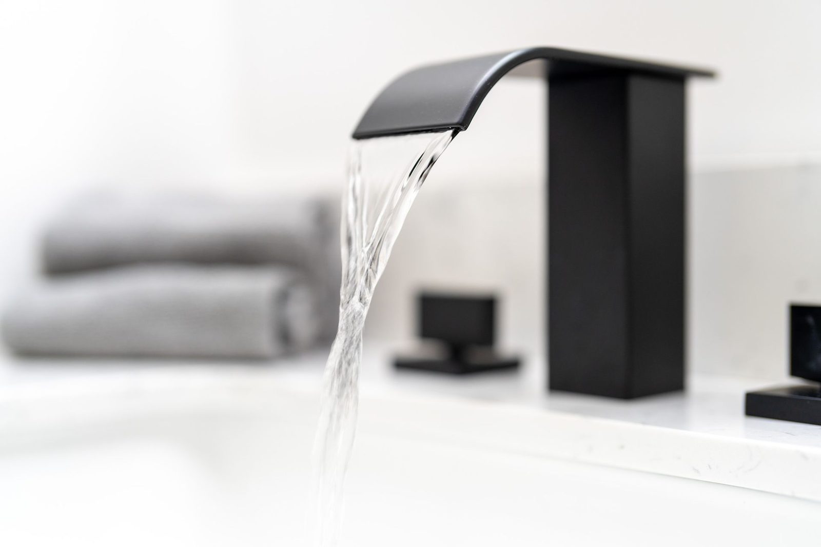 A black faucet is pouring water into a bathtub.