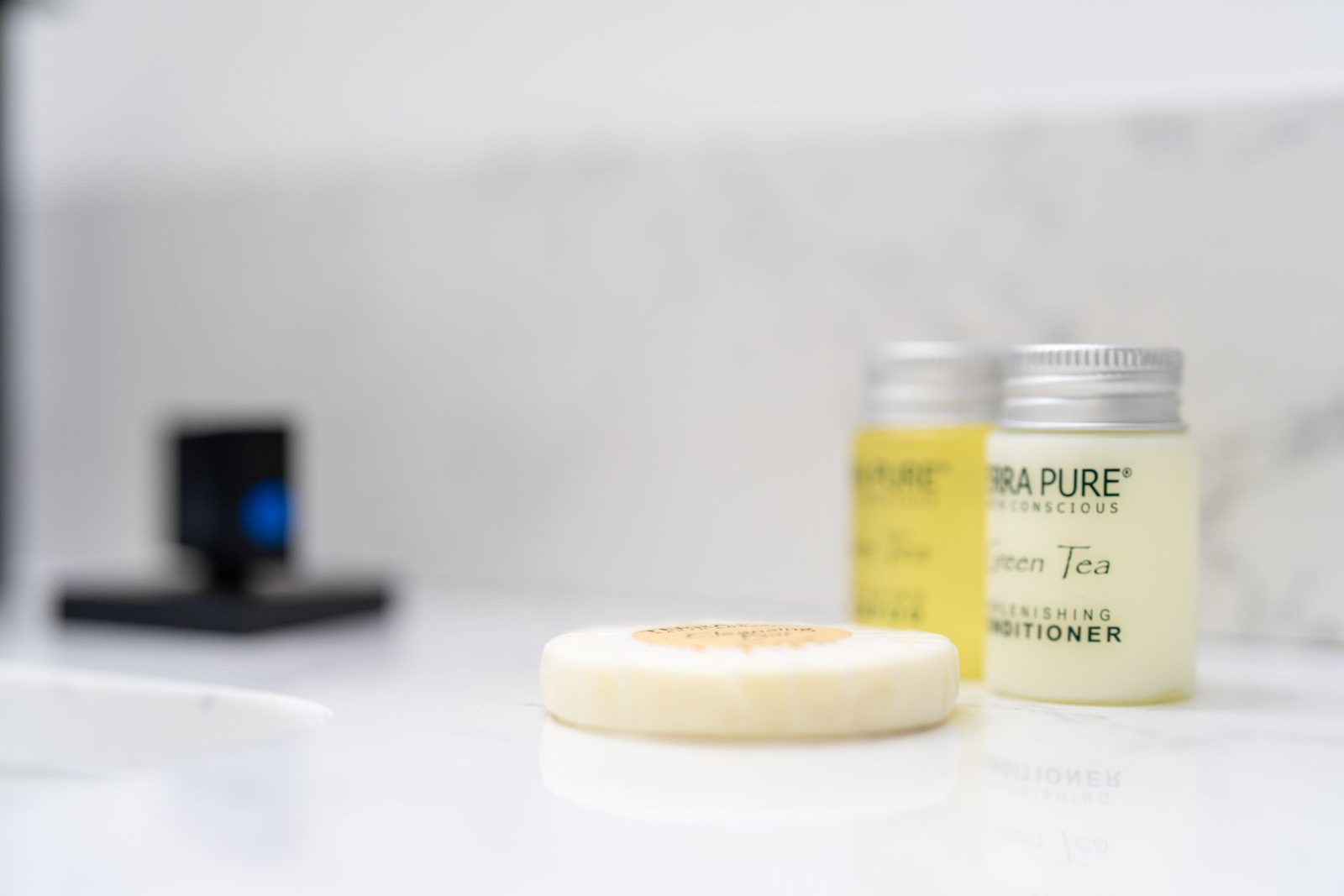 A soap bar and two bottles of conditioner are on a bathroom counter.