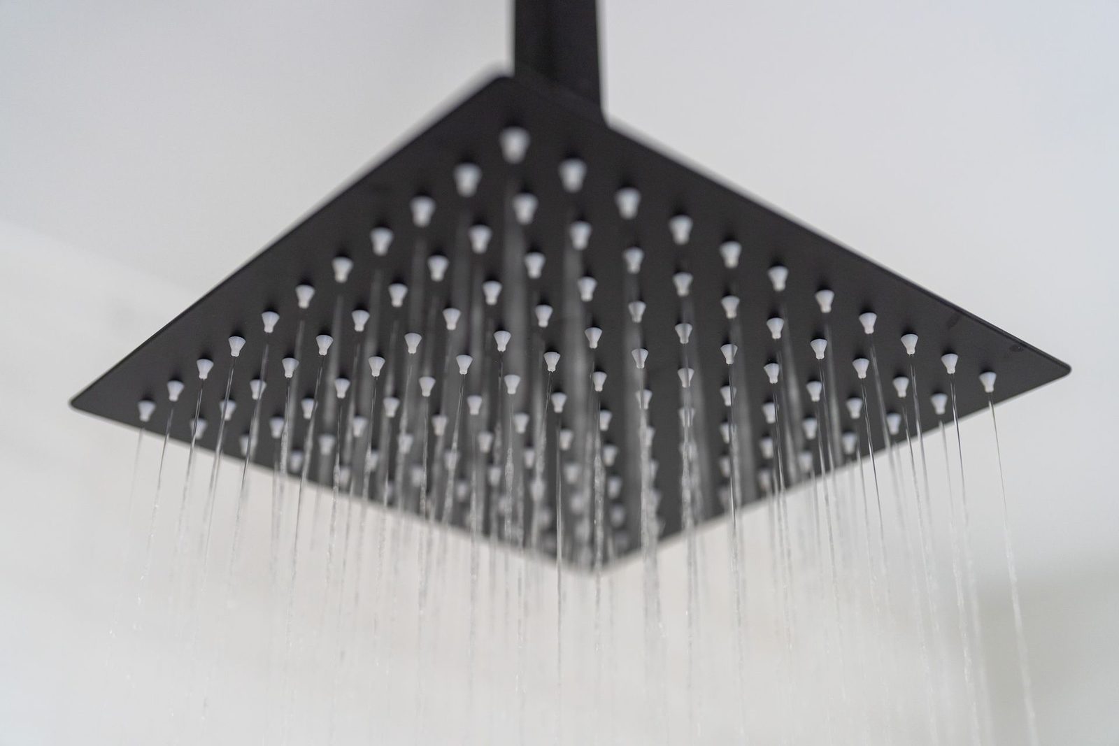 A close up of a black shower head with water coming out of it.