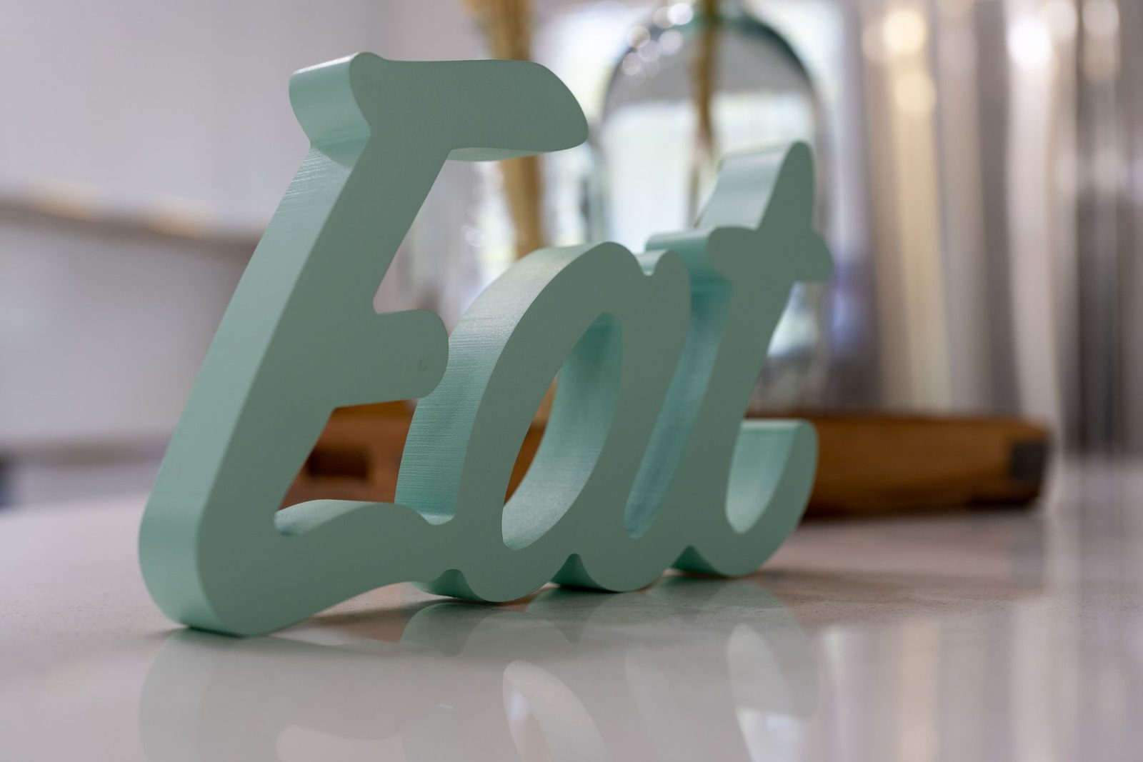A wooden sign that says eat is sitting on a counter.