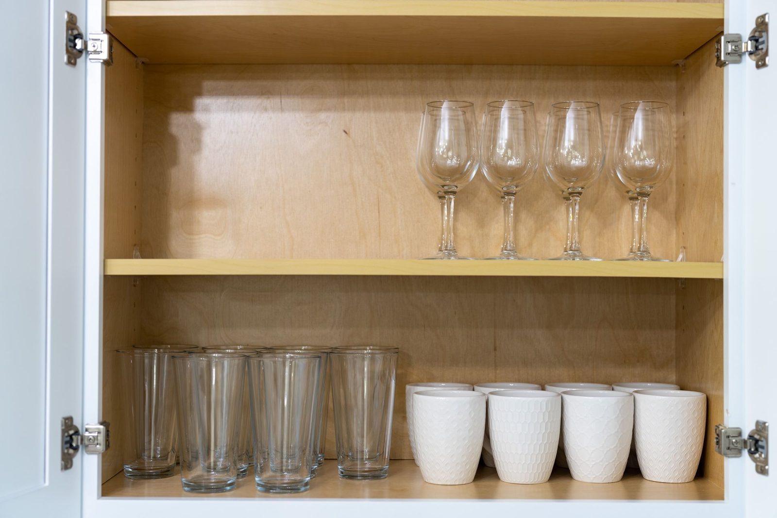 A kitchen cabinet filled with cups and wine glasses.