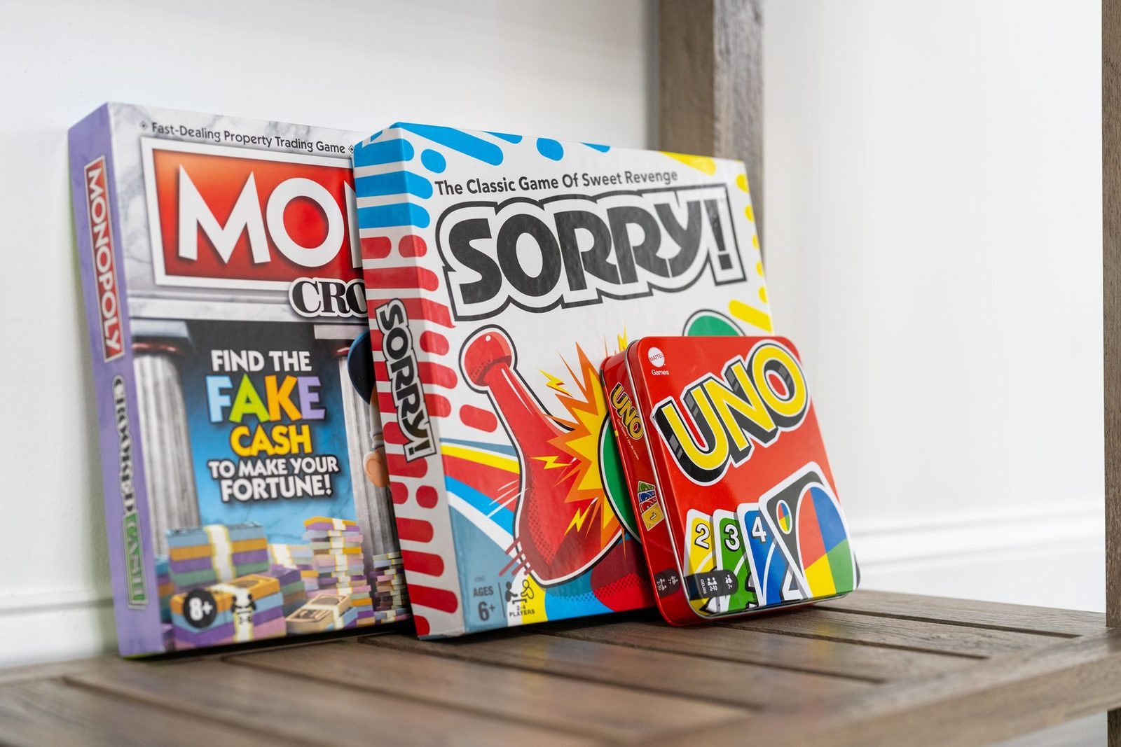 Three board games are sitting on a wooden shelf.