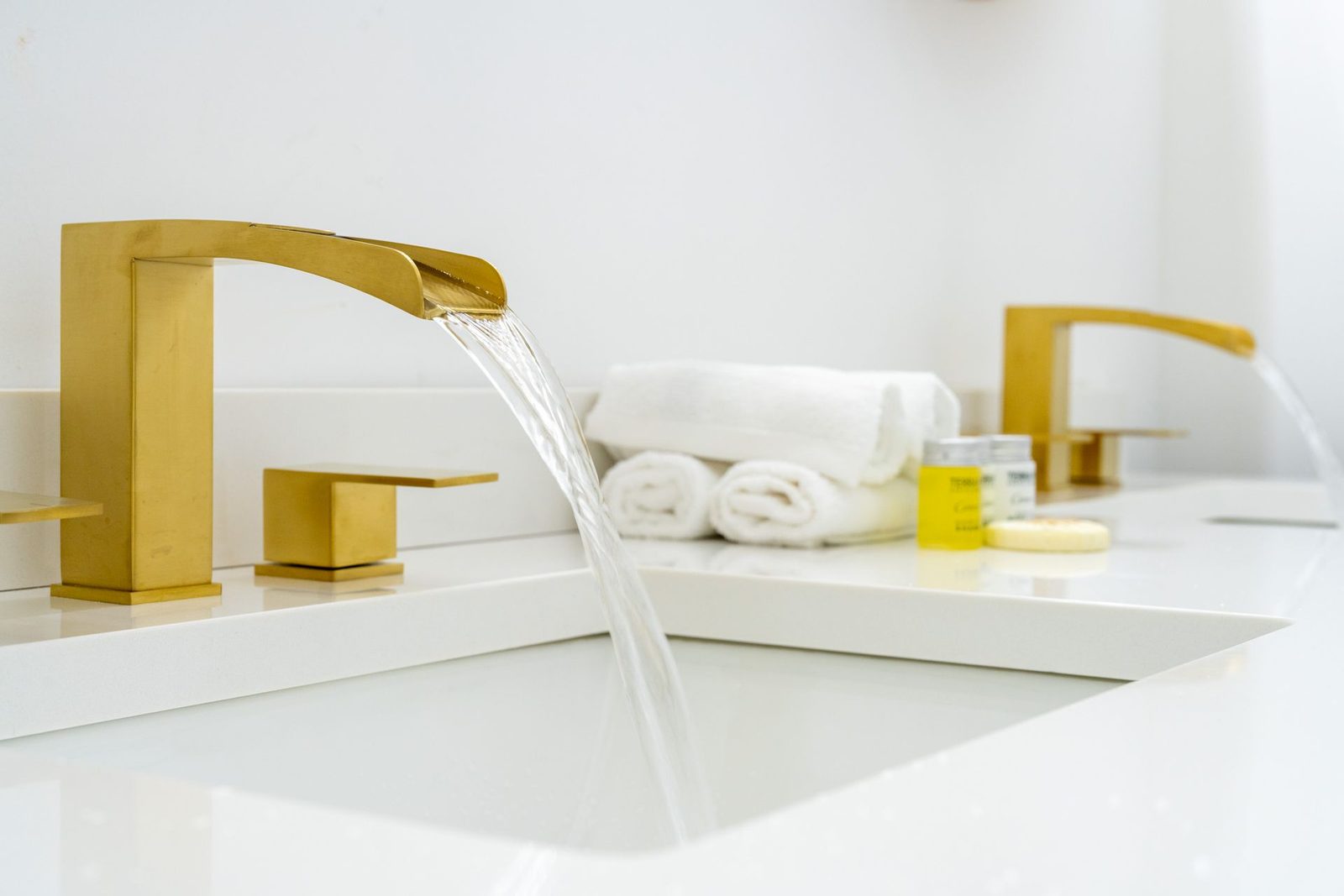 A bathroom sink with gold faucets and towels on the counter.