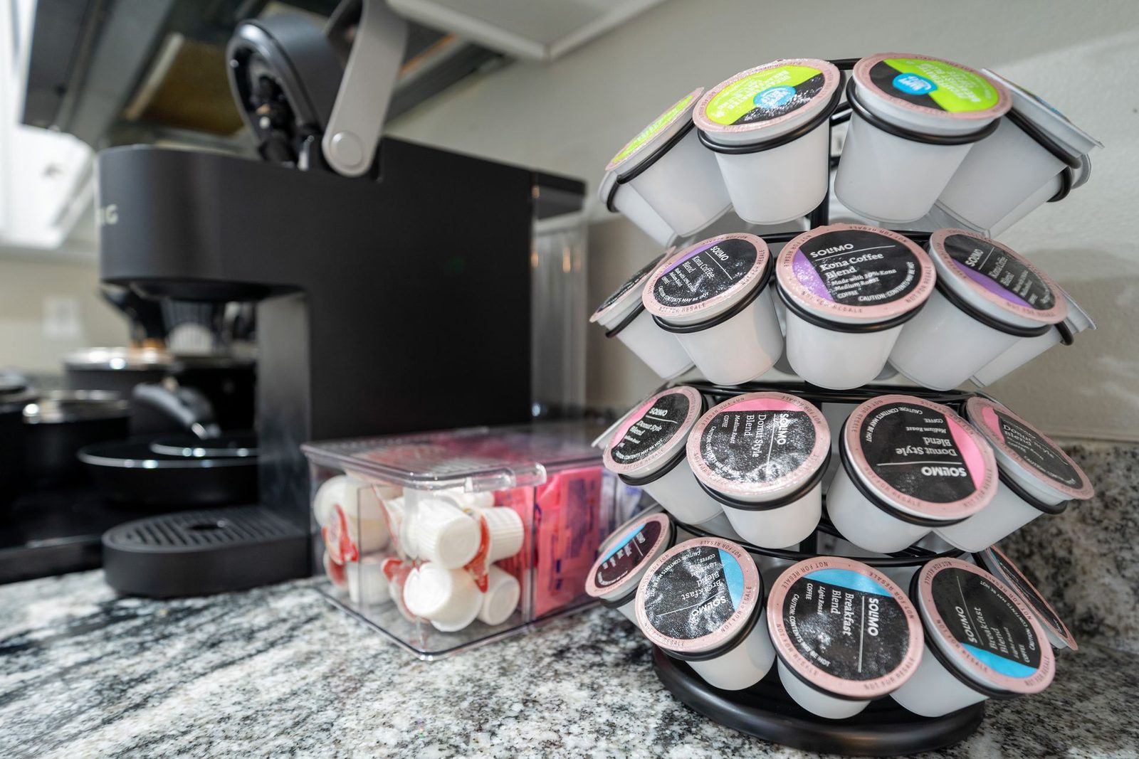 A stack of k cups are sitting on a counter next to a coffee machine.