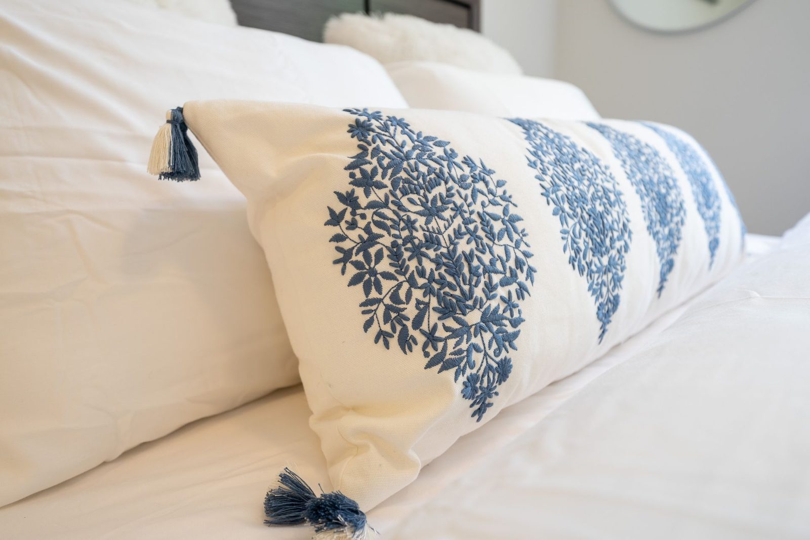 A blue and white pillow is sitting on top of a bed.