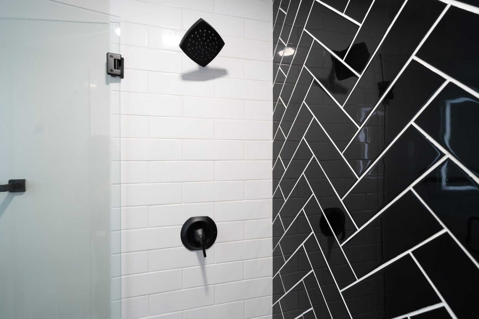 A bathroom with black and white tiles and a black shower head.
