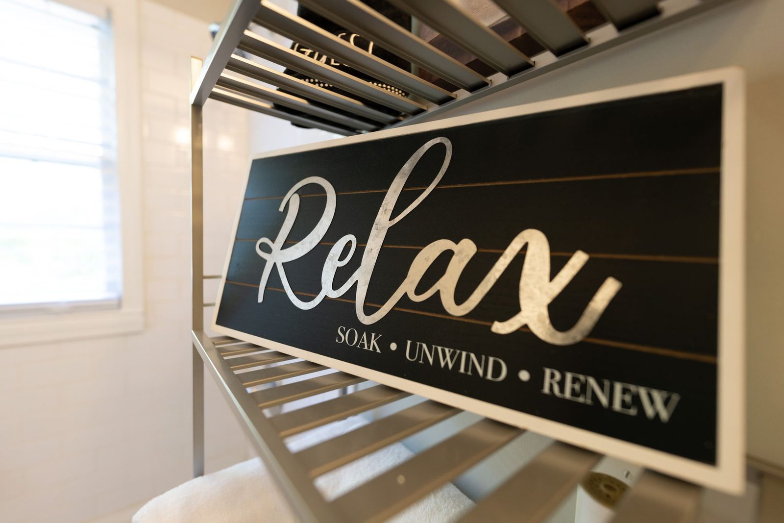 A sign on a shelf that says relax soak unwind renew