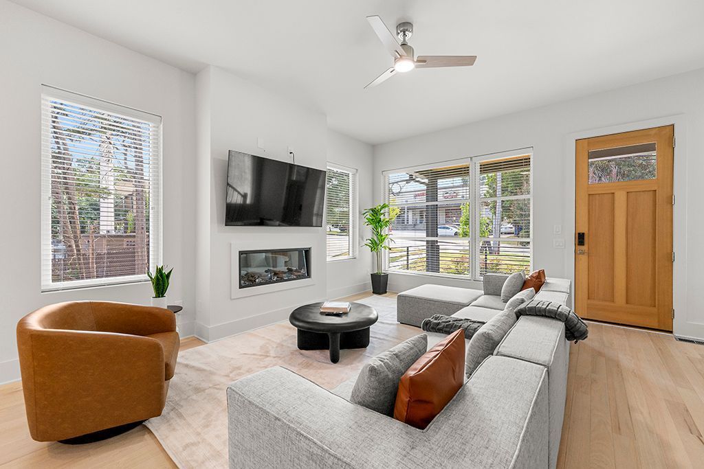 Modern living room with light wood floors, gray sectional sofa, and tan accent chair.