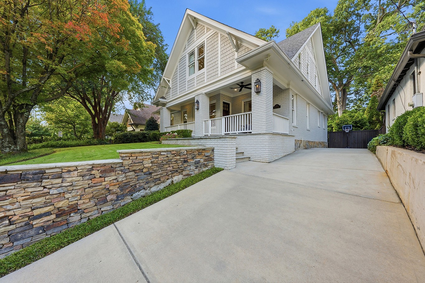 White home with a covered front porch, landscaped lawn, and stone retaining wall on Yorkshire Road in Atlanta