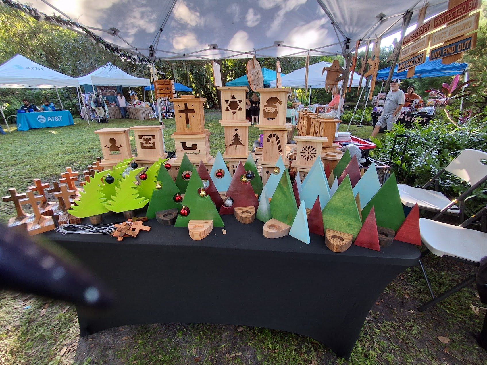 Colorful wooden Christmas trees and holiday lanterns displayed at our craft-fair table