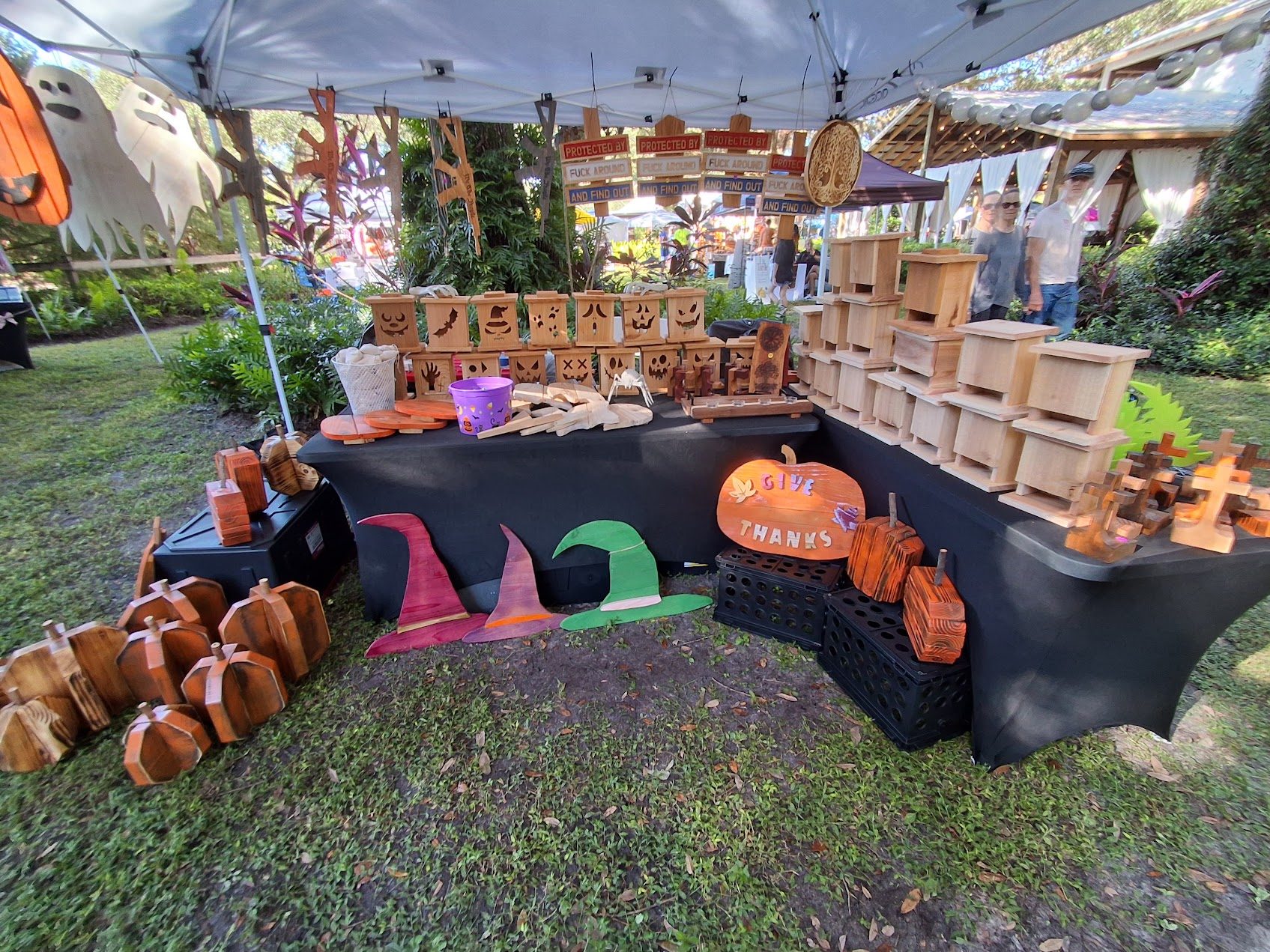 Handmade Halloween lanterns, witch hats, wooden pumpkins, and a Give Thanks sign at the fair
