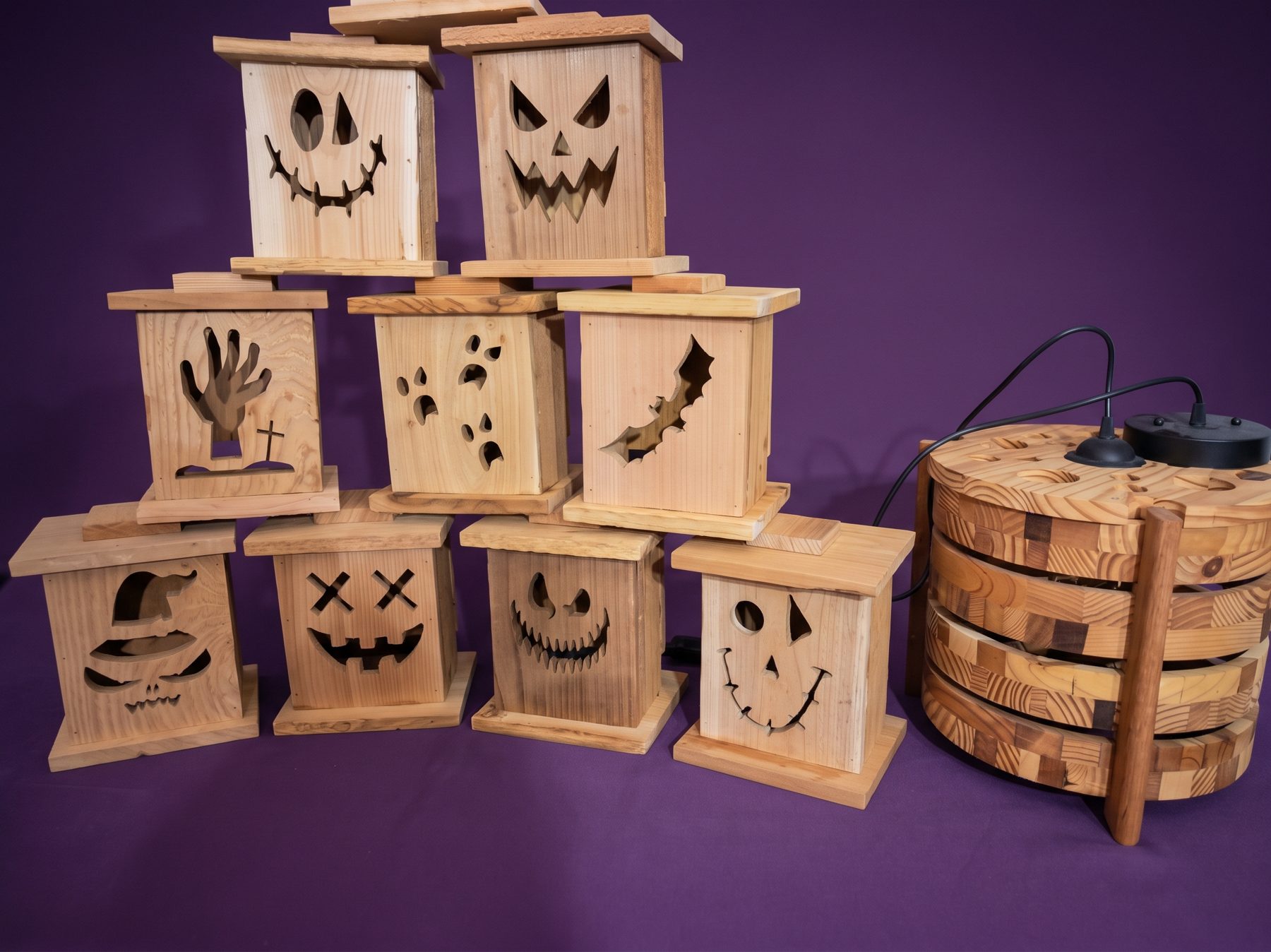 Wooden Halloween lanterns with pumpkin, ghost, bat, and skeleton cutouts beside a wood pendant light