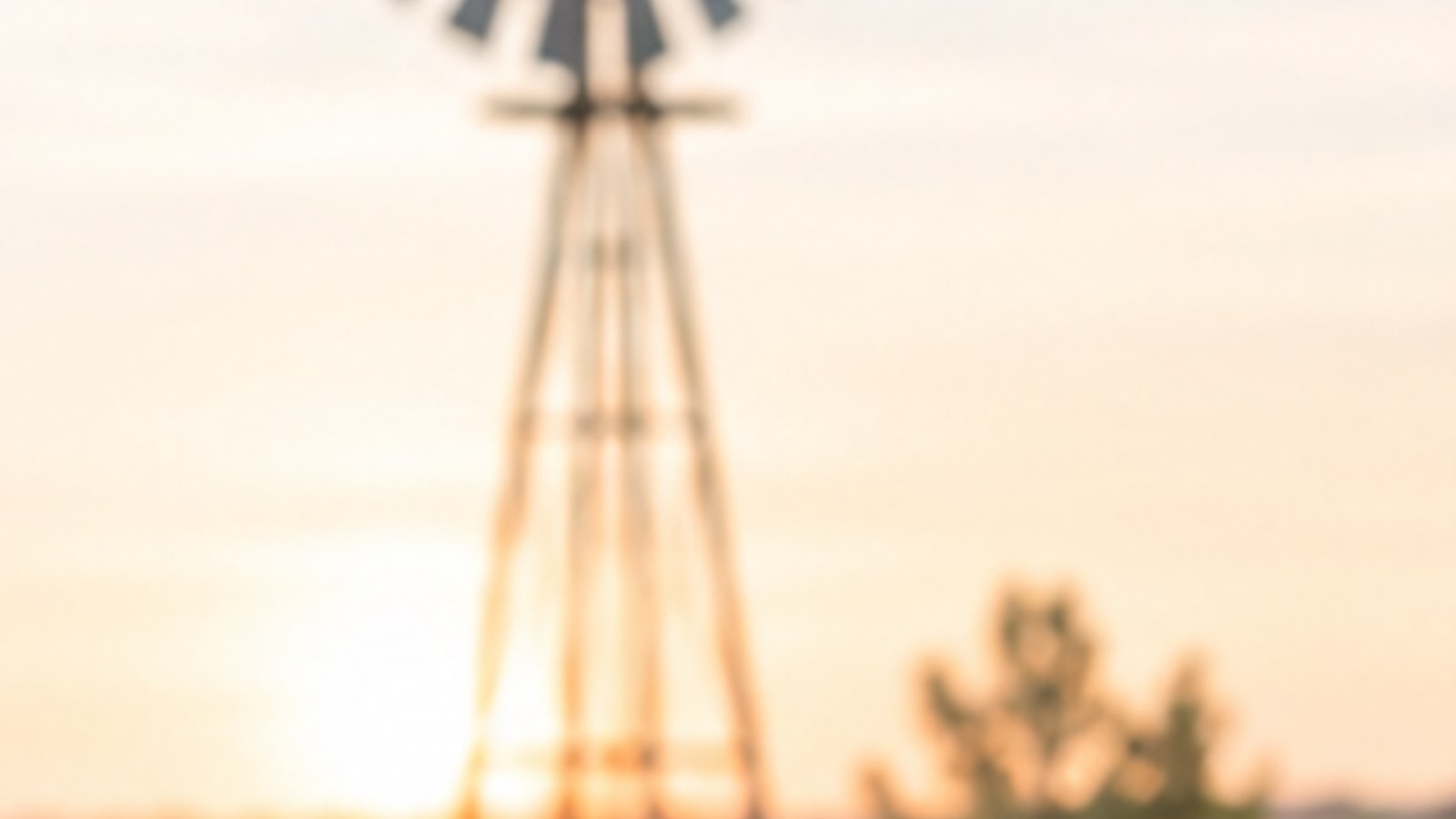 A windmill standing in a softly lit field at sunset
