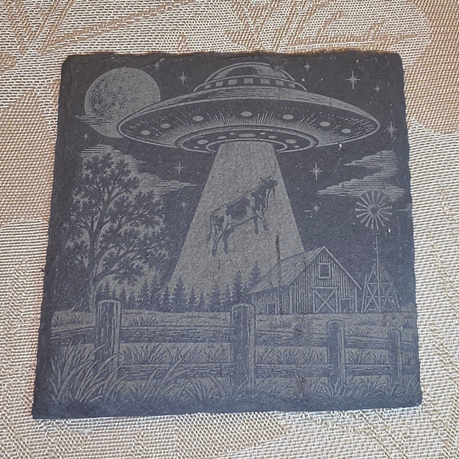 Cow Abduction alien slate coaster on a tabletop