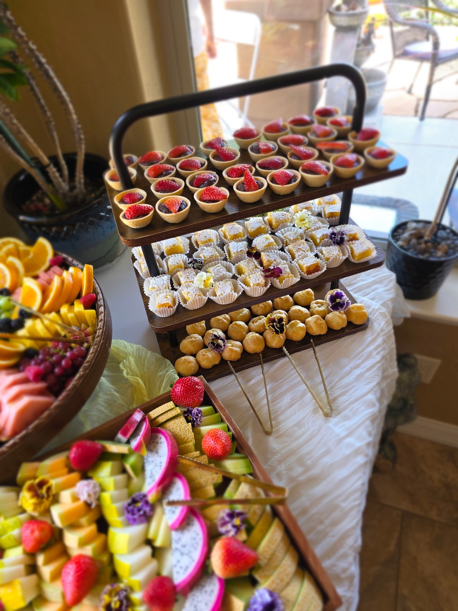 A tiered wedding dessert display with individual sweets, fruit, and pastries