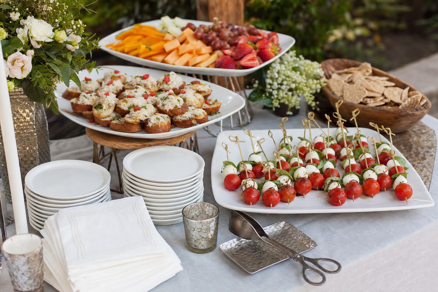Caprese skewers, crostini, fruit and plates arranged for wedding cocktail-hour guests