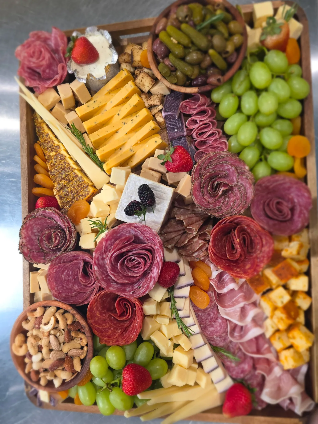 A charcuterie box with a salami rose and fruit