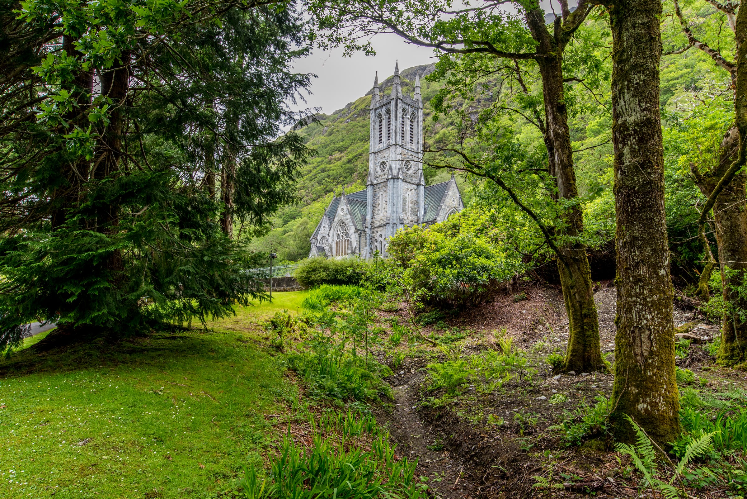 Stone church framed by woodland and a green hillside