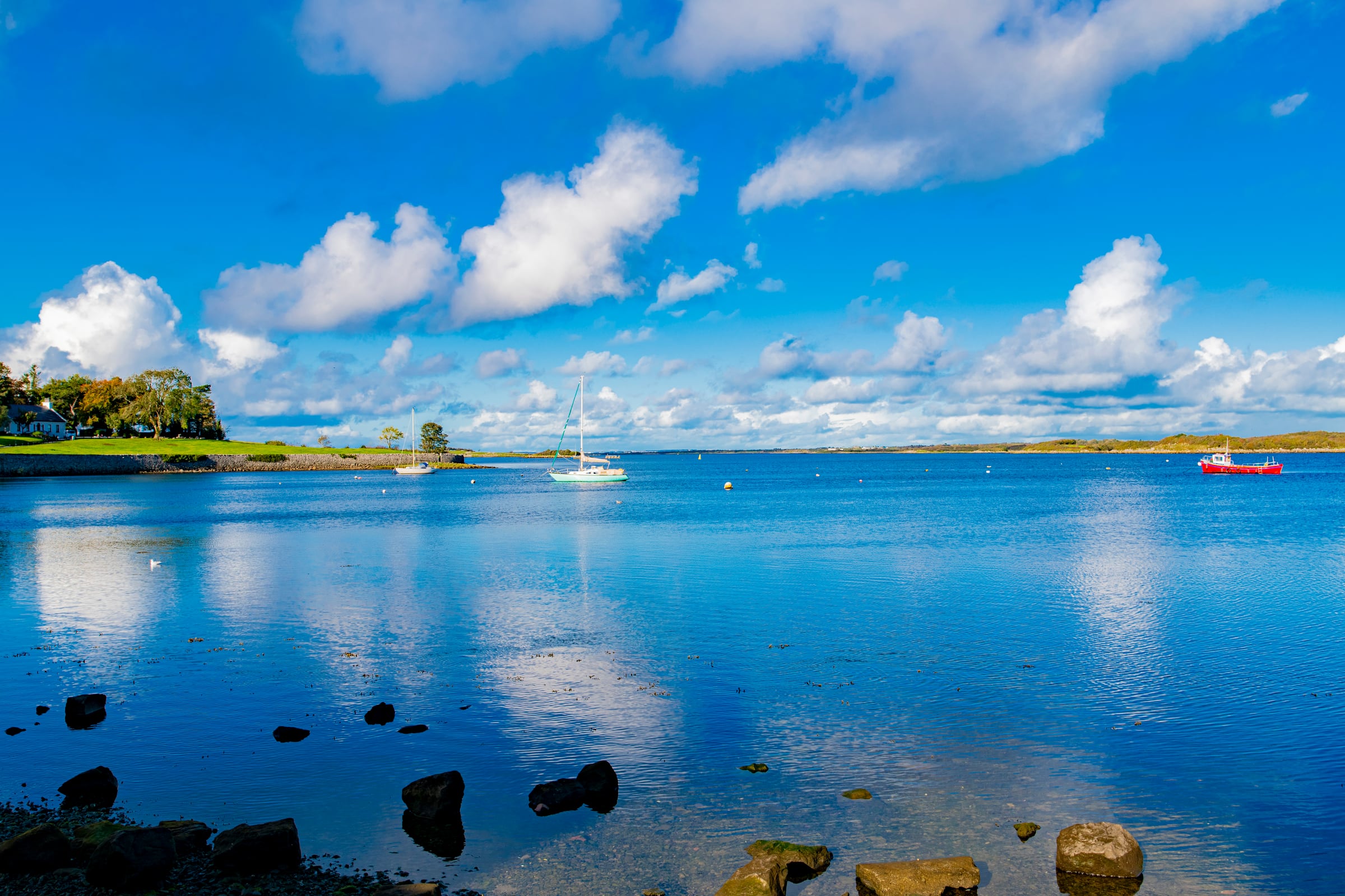 Boats on a bright Irish harbour beneath a blue sky