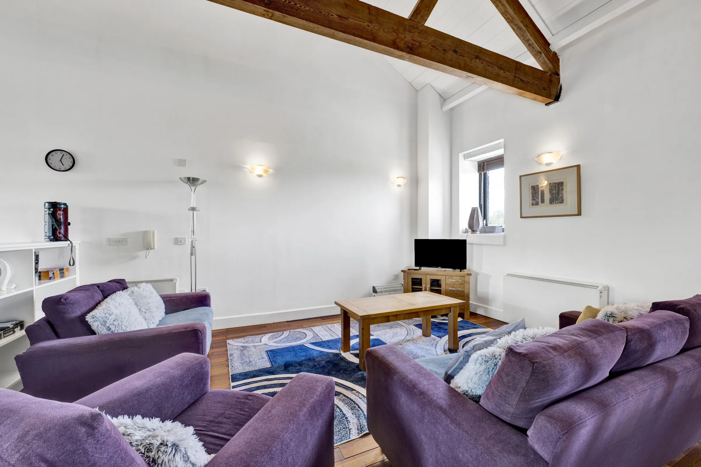 Living room with purple seating and exposed timber beams