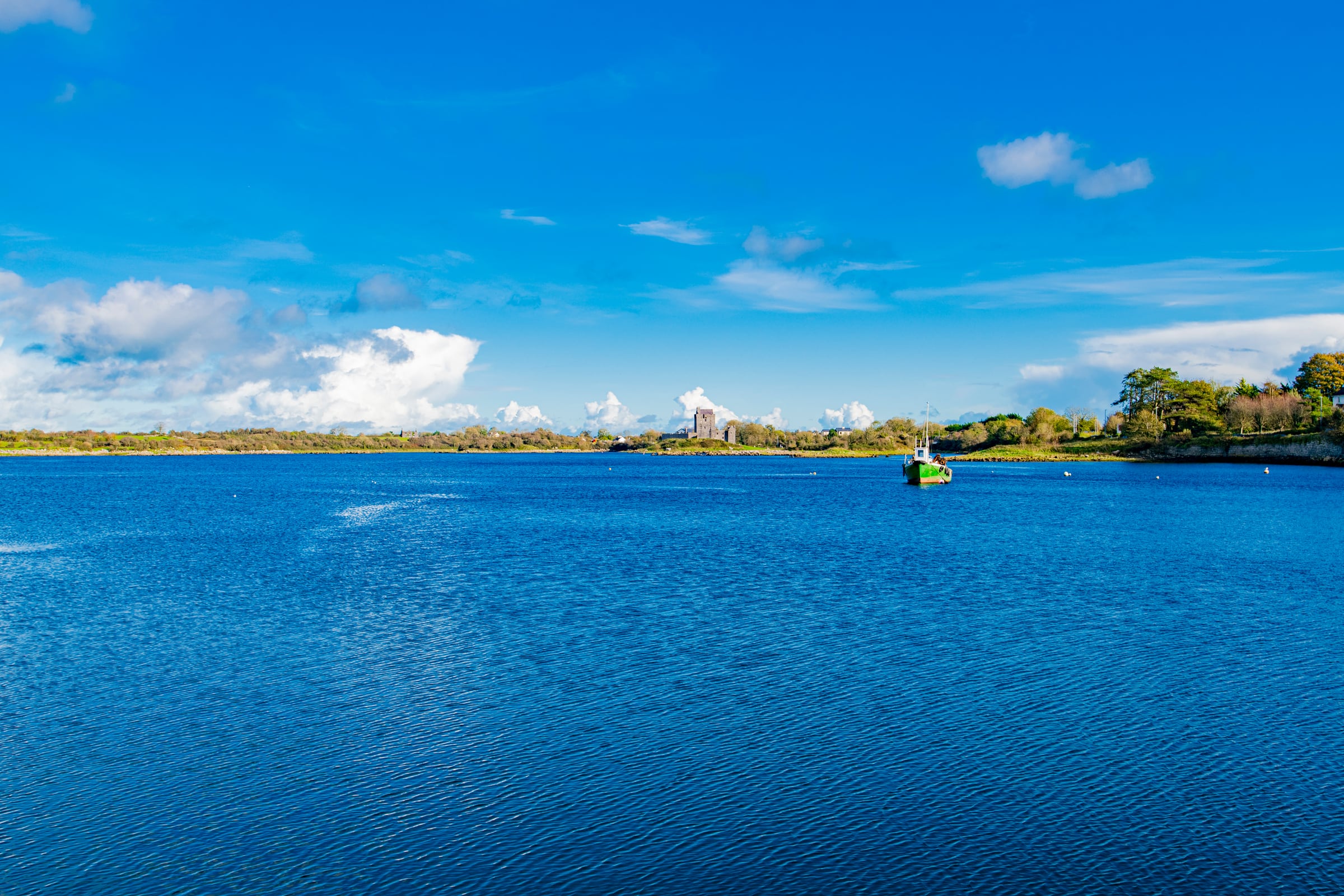 Castle across blue water with a green fishing boat