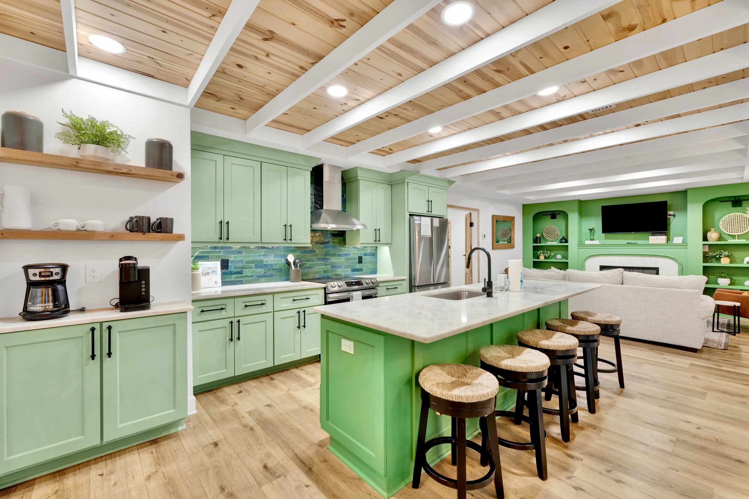 Green kitchen opening into a bright living room