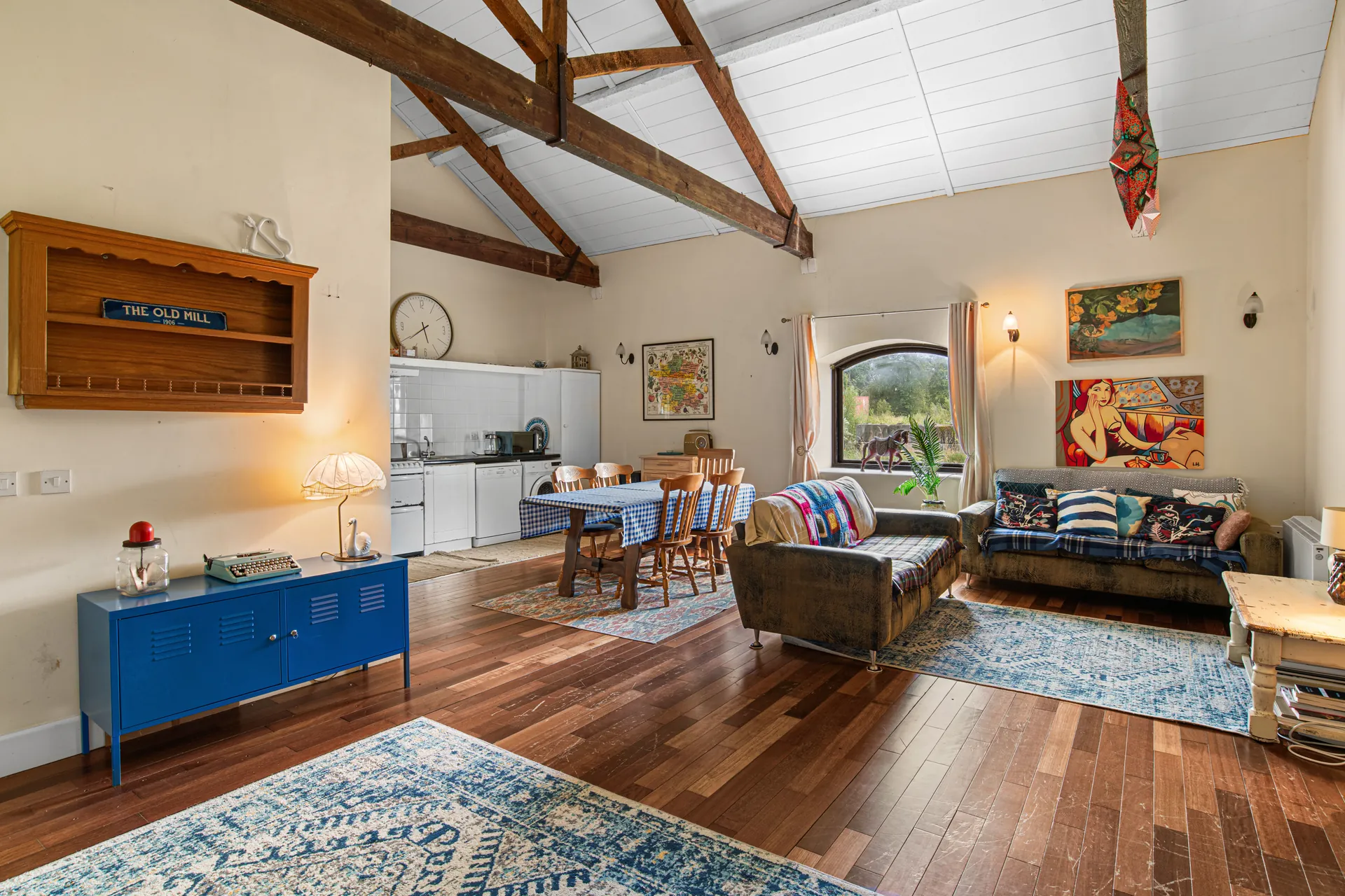 Before virtual renovation: open-plan living room and dated kitchen with exposed timber beams
