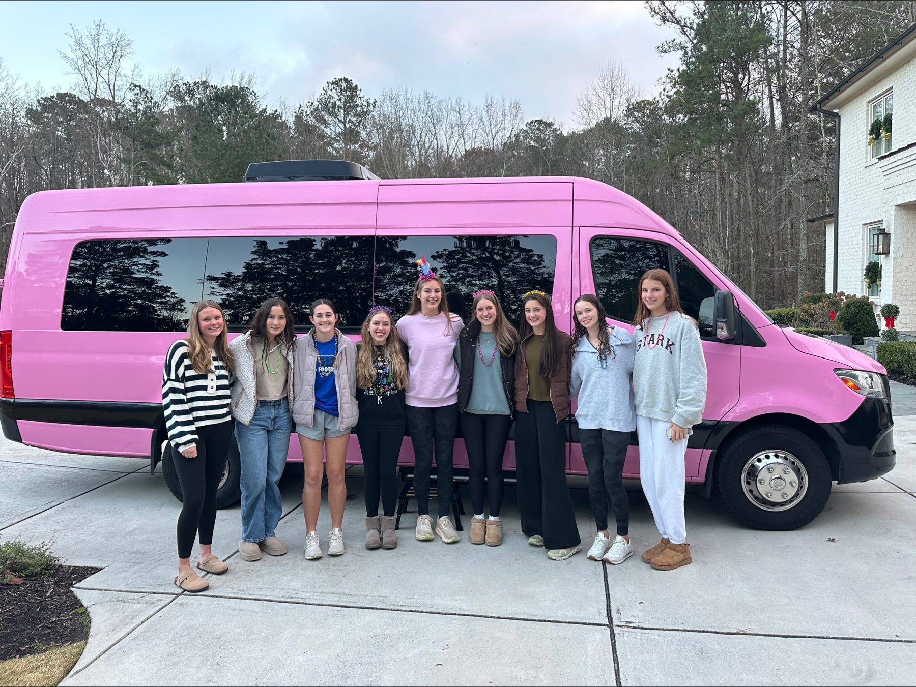 Group posing beside a pink passenger van