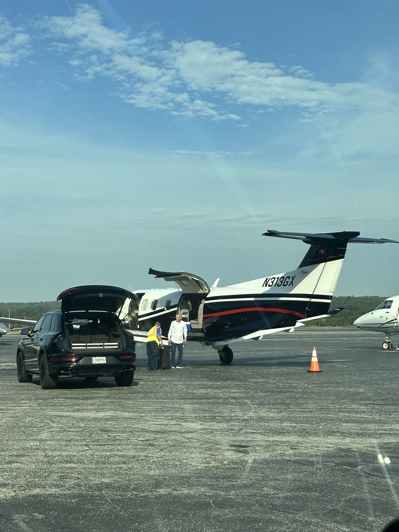 SUV awaiting passengers beside a private aircraft