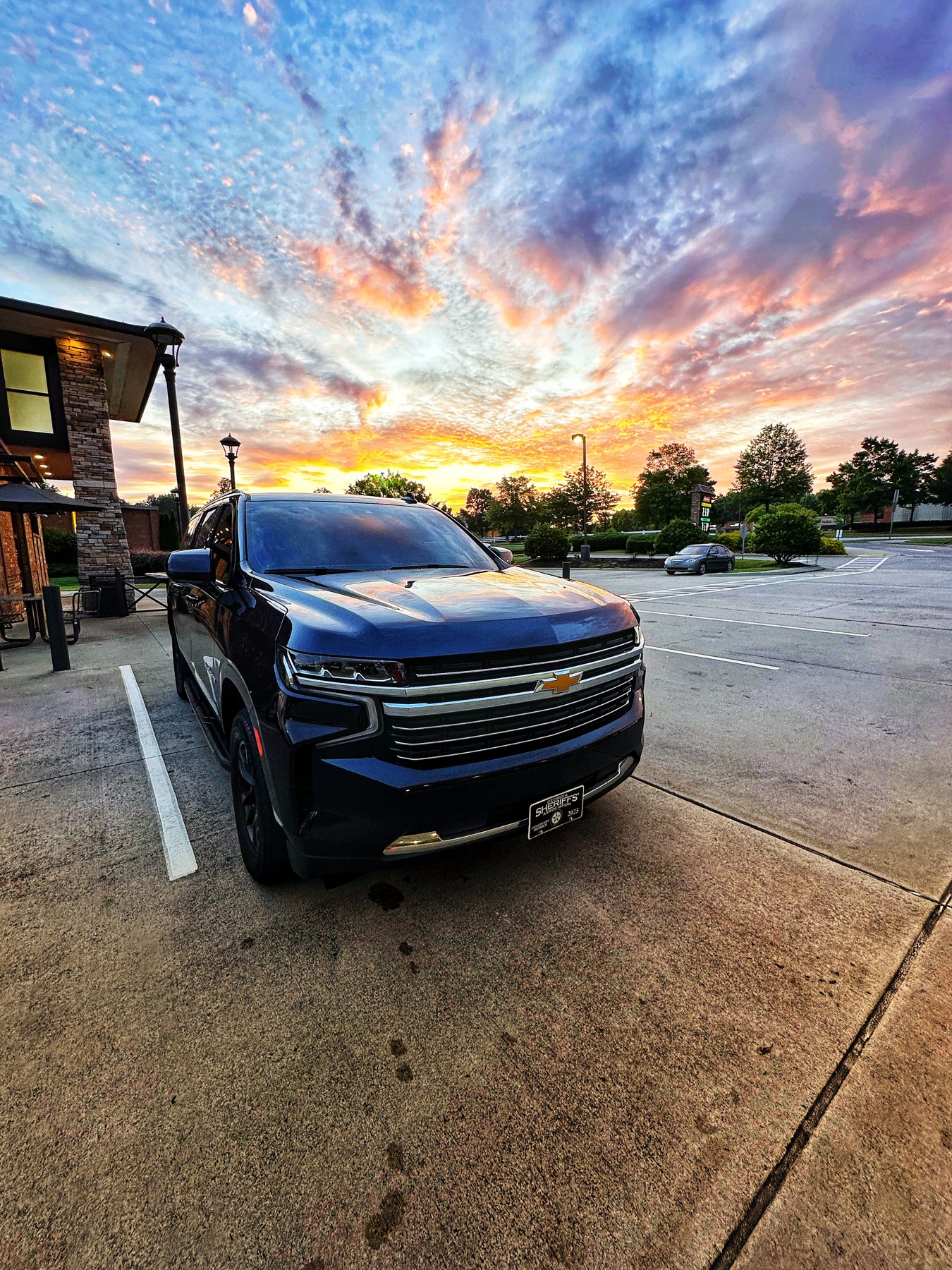 Black SUV beneath a colorful evening sky