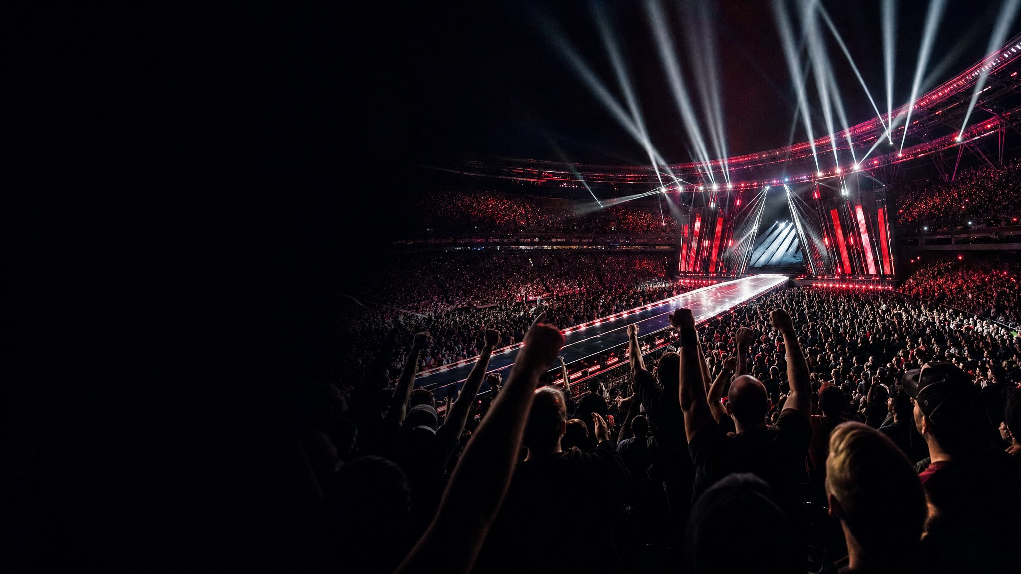 Fans watching a major stadium entertainment event with a bright entrance ramp