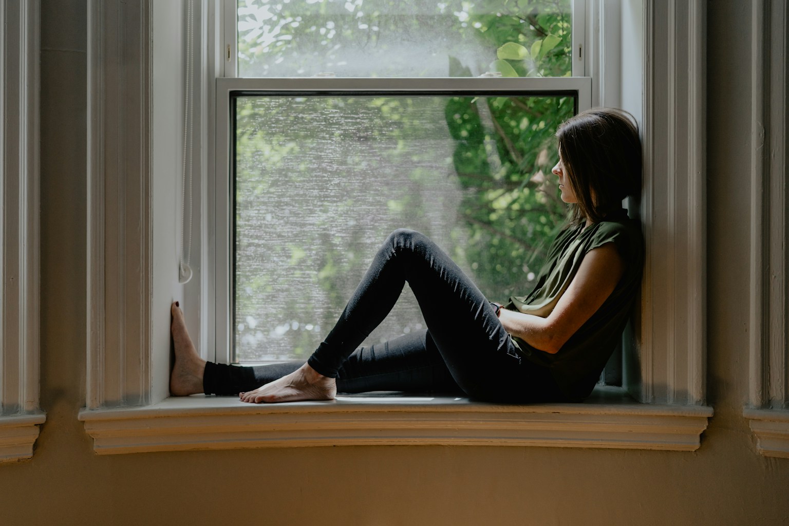 Woman taking a quiet pause beside a sunlit window