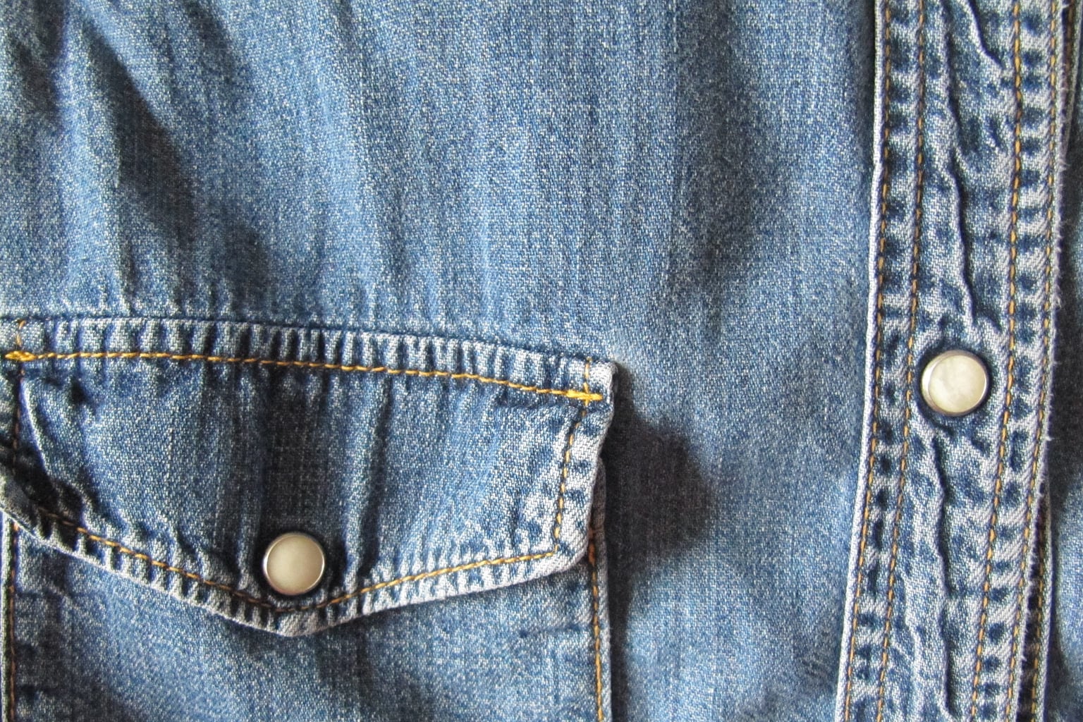Close view of a blue denim work shirt pocket and snap placket