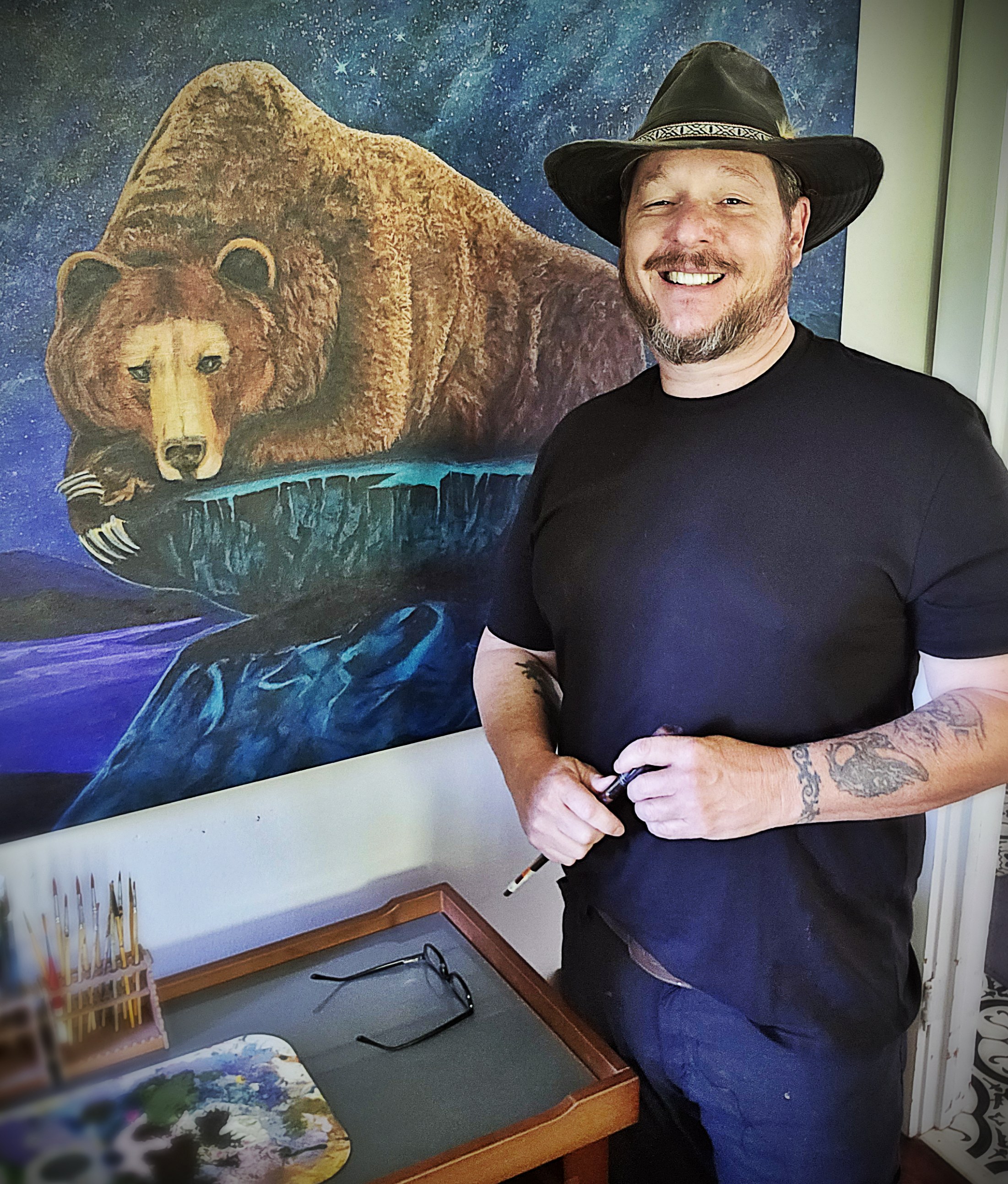 Waylon Christner in his studio beside a bear painting