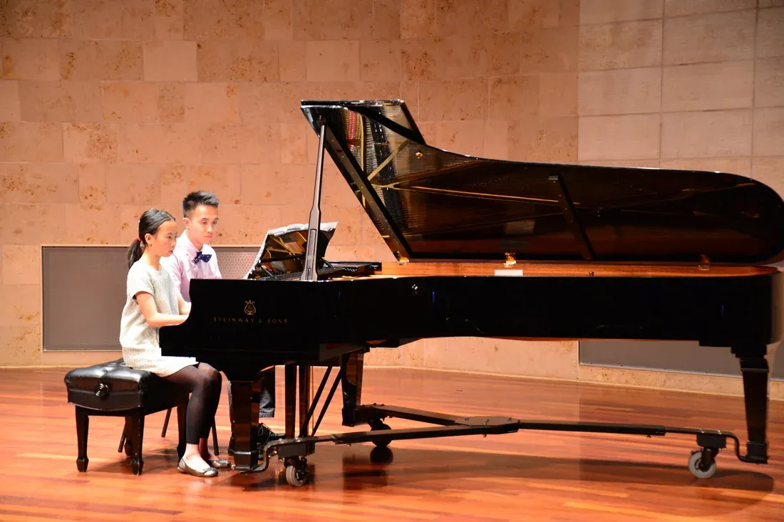 teacher guiding a child at the piano