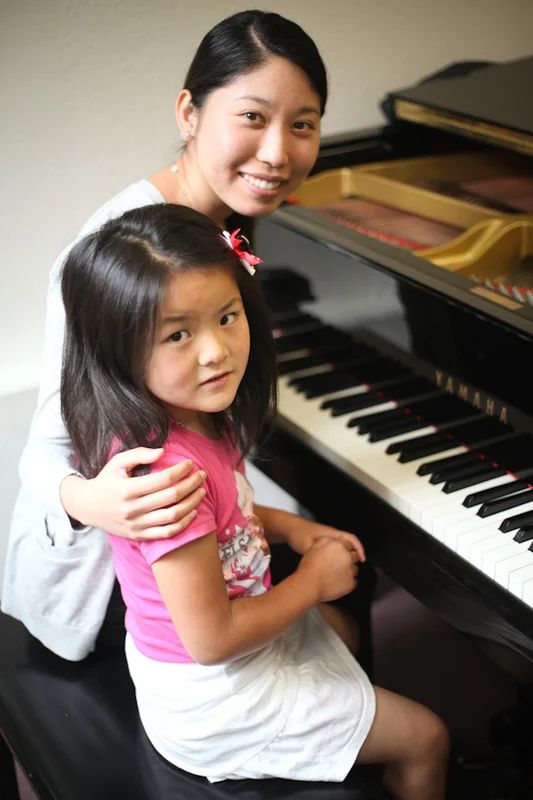 Young Amabile piano student sitting with an adult at a grand piano