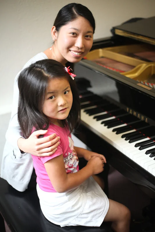 young beginner at piano with teacher guidance
