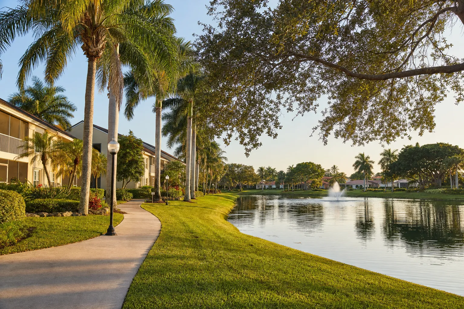 Palm-lined walking path beside a lake in a South Florida residential community